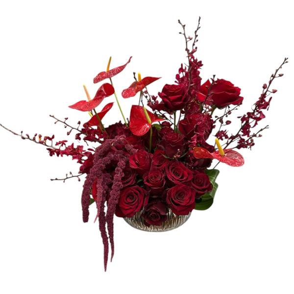 Red rose arrangement in a clear glass bowl with red anthuriums