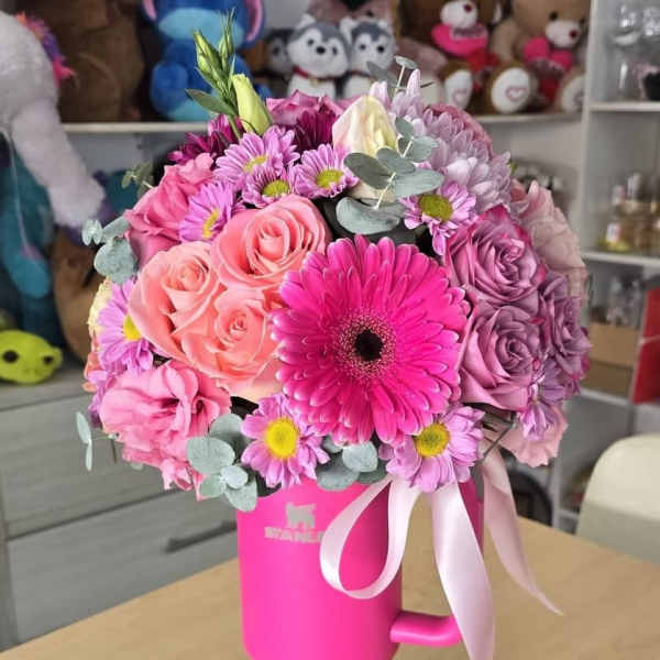 Pink and purple bouquet in a bright pink mug-shaped vase with ribbon