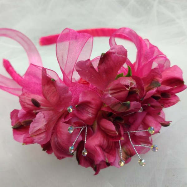 Pink floral headpiece with ribbon loops and rhinestone accents