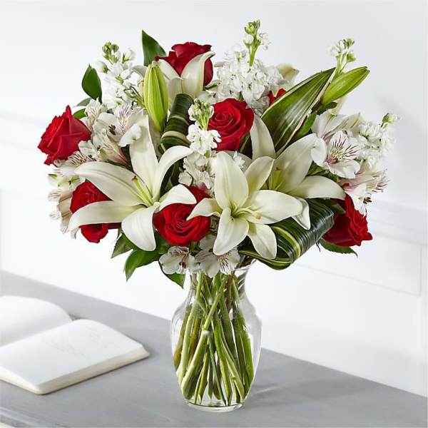 Bouquet of red roses and white lilies in a clear glass vase