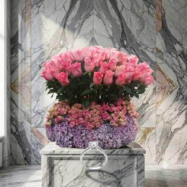 Large arrangement of pink roses and lavender flowers on a marble pedestal