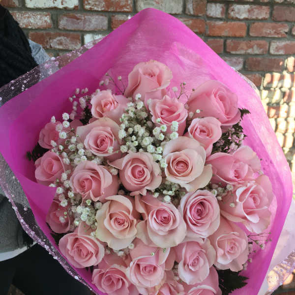 Bouquet of pale pink roses with baby's breath in bright pink wrap