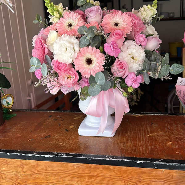 Pink and white bouquet in a white vase with a pink ribbon