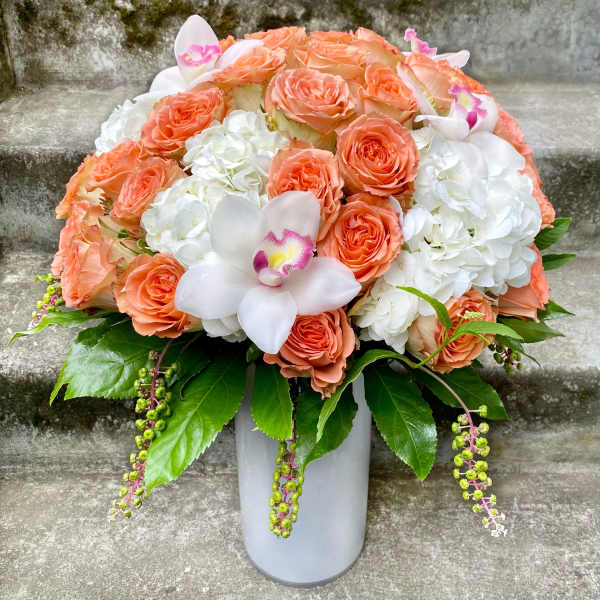 Peach roses and white hydrangeas in a gray vase with white orchids