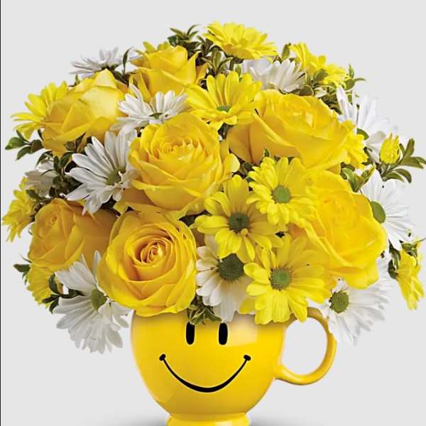 Yellow roses and white daisies in a smiley-face mug