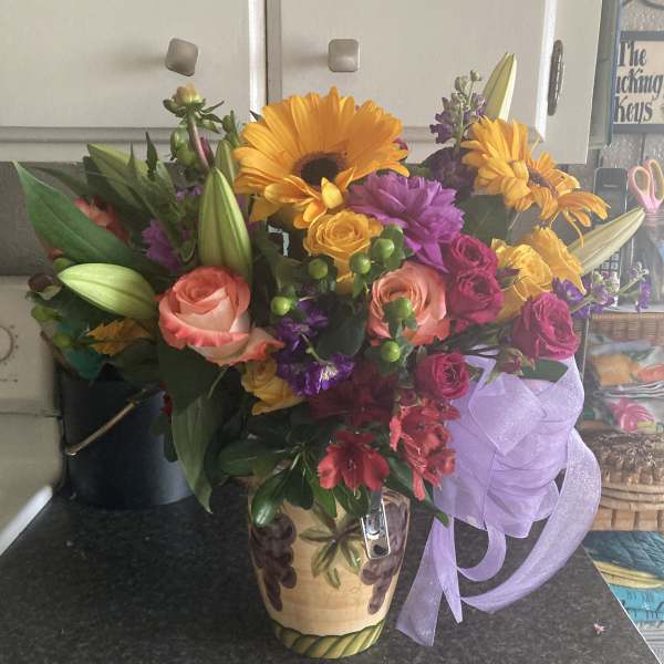Mixed bouquet in a decorative vase with a purple ribbon