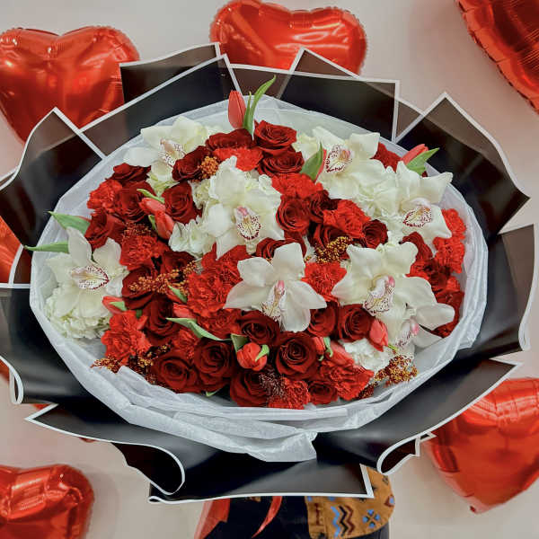 Red and white bouquet surrounded by red heart balloons