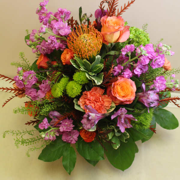 Mixed bouquet with orange roses, purple blooms, and green accents