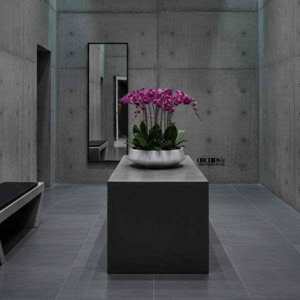 Pink orchids arranged in a white bowl on a pedestal