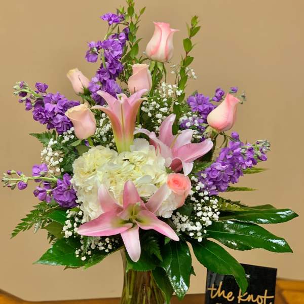 Pink lilies and roses with purple stock in a glass vase