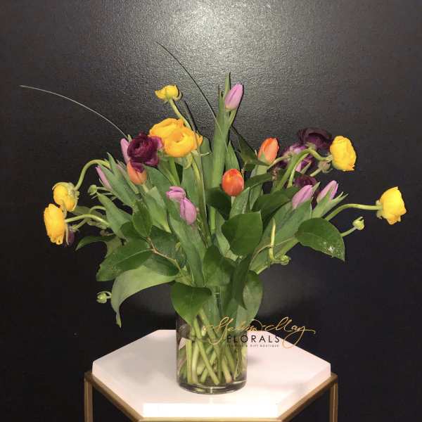 Colorful tulips in a clear glass vase on a small table