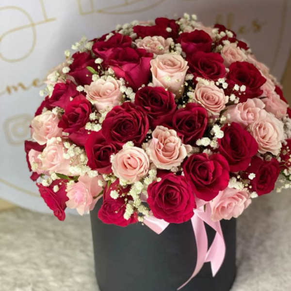Bouquet of red and blush roses in a black hat box with a pink ribbon