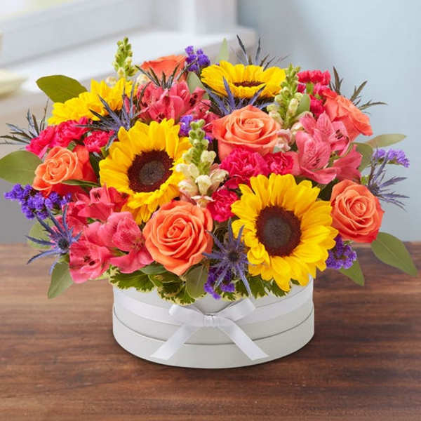 Bright mixed bouquet with sunflowers and roses in a white hat box
