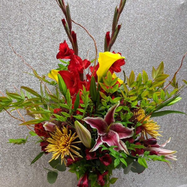 Tall mixed bouquet with red and yellow flowers in a glass vase