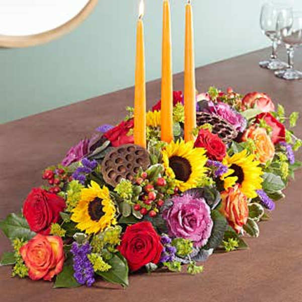 Colorful floral centerpiece with three orange candles