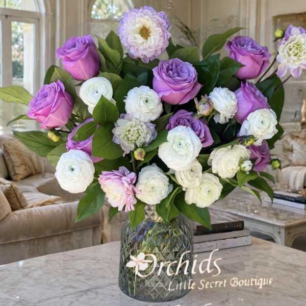Purple and white flower arrangement in a glass vase