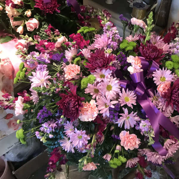 Large pink and purple floral arrangement with a purple ribbon