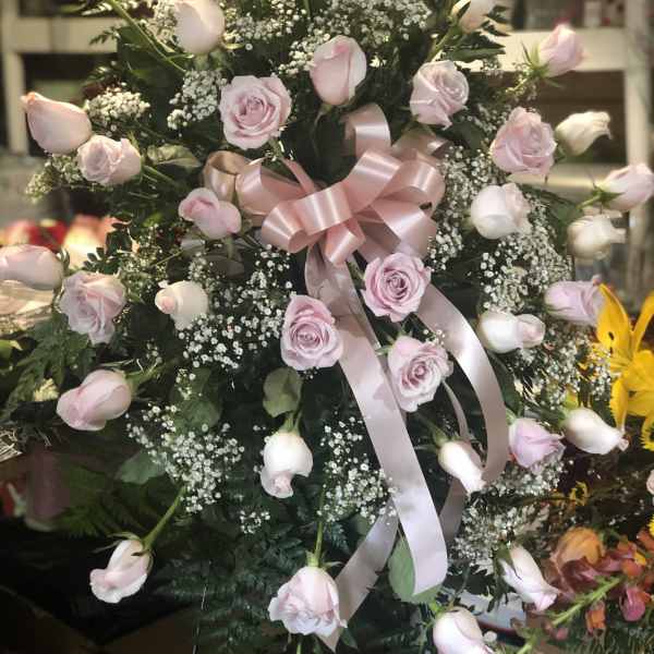 Pink roses and rosebuds arranged with baby's breath and a pink ribbon bow