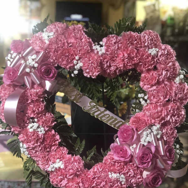 Pink floral heart wreath with roses and ribbon on a stand