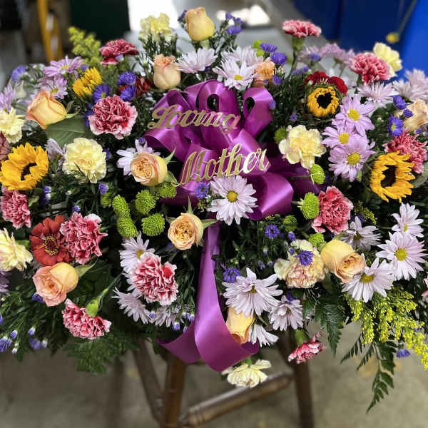 Large floral spray with a purple ribbon and "Loving Mother" sign