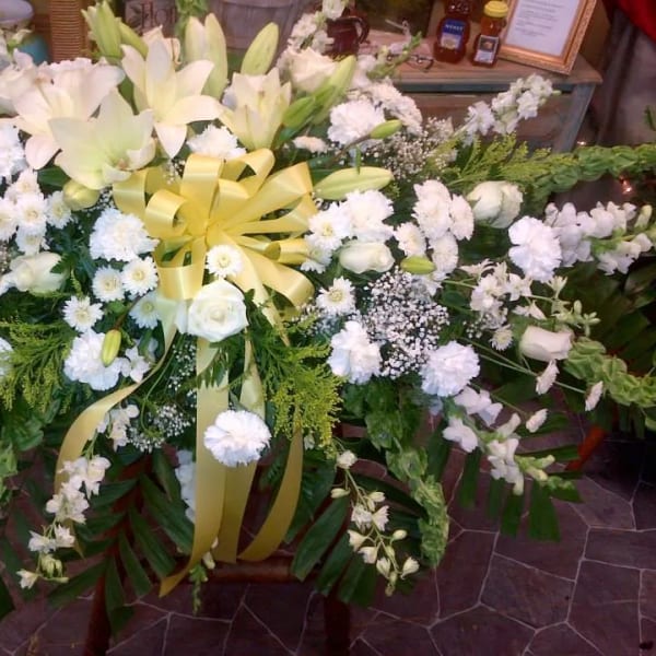 Large white floral spray with lilies, roses, and a yellow ribbon