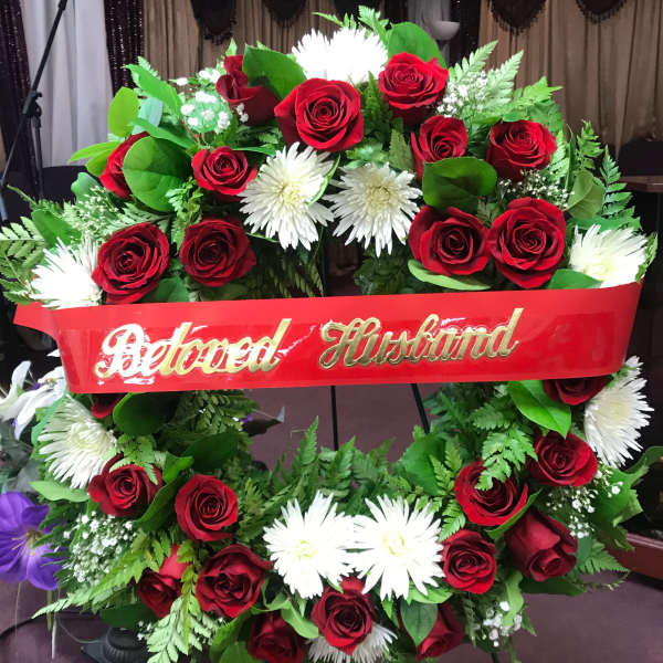 Red rose and white daisy funeral wreath with a red ribbon