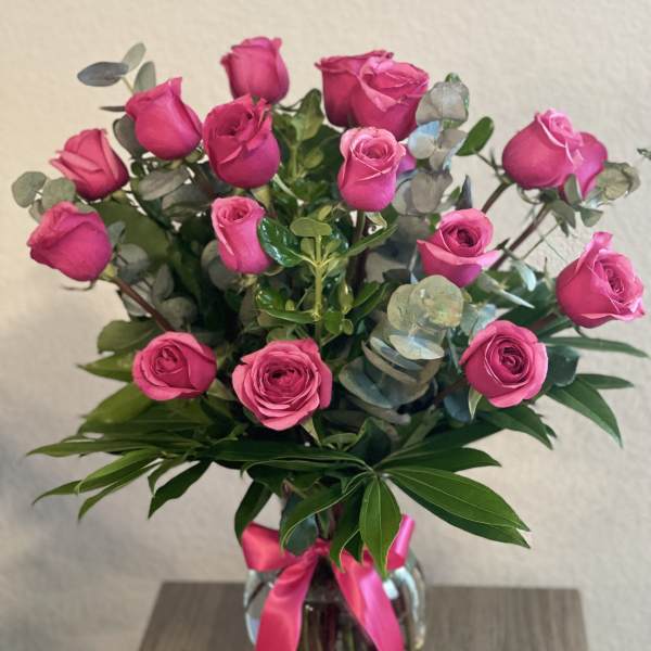 Pink roses in a glass vase with a pink ribbon