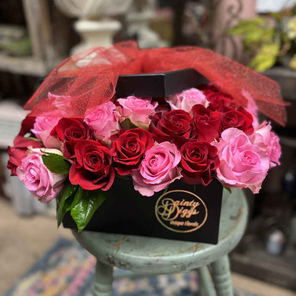 Boxed arrangement of red and pink roses with red tulle