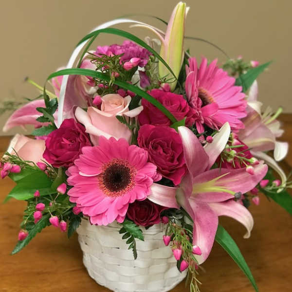 Pink and white mixed flower arrangement in a white basket