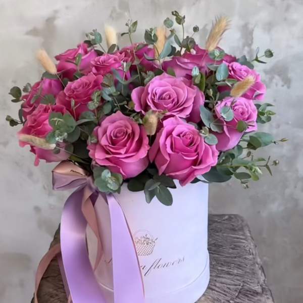 Pink roses arranged in a white hat box with a ribbon