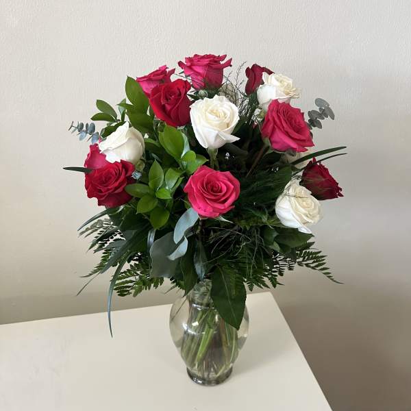 Bouquet of red, pink, and white roses in a clear glass vase