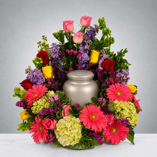 Colorful funeral urn surround with roses, gerberas, and hydrangeas