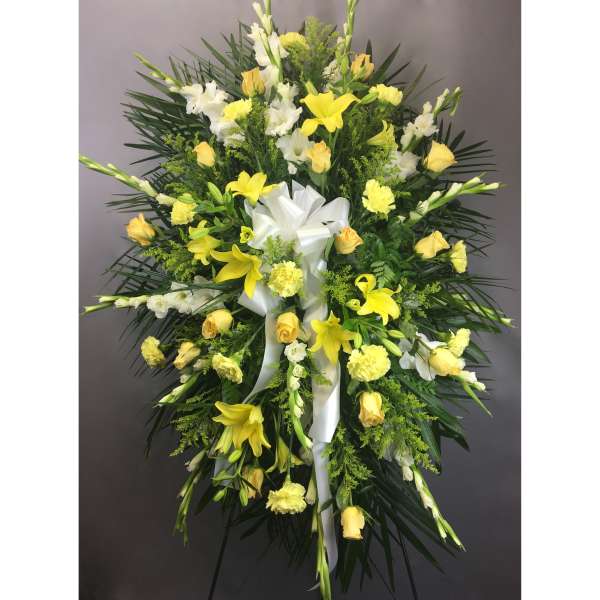 Standing floral spray with yellow and white flowers and a white ribbon