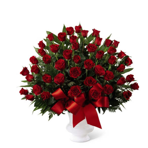 Large arrangement of red roses in a white pedestal vase with a red bow