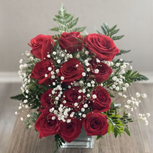 Red roses with baby's breath in a clear glass vase
