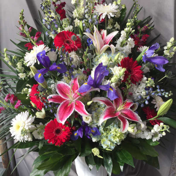 Large mixed bouquet with lilies, gerberas, irises, and white daisies in a white vase