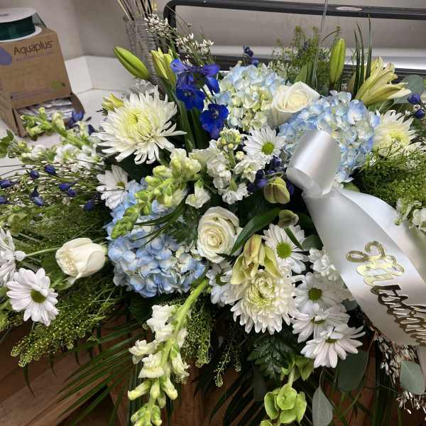 Large white and blue floral spray with a silver ribbon