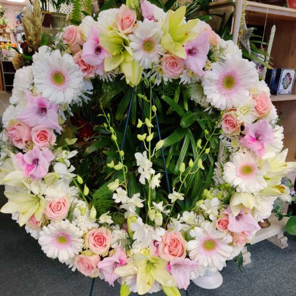 Large heart-shaped floral wreath with pink and white flowers on an easel