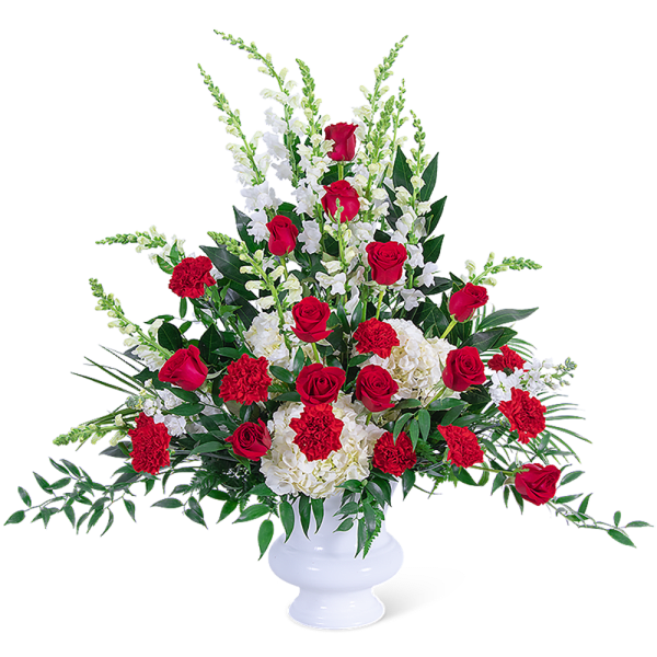 Red roses and white flowers arranged in a white urn vase