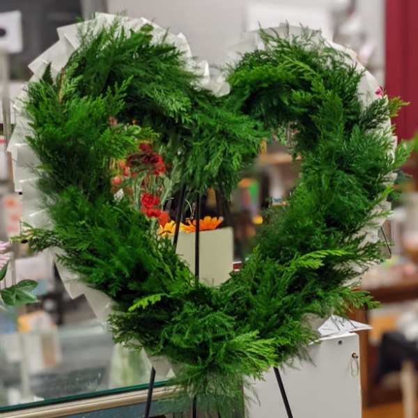 Heart-shaped green wreath on a stand with white wrapping