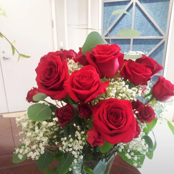 Red roses arranged in a clear glass vase with white baby's breath
