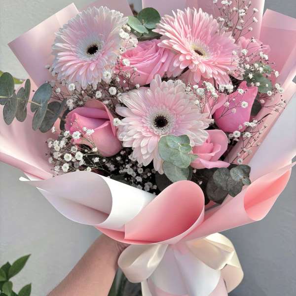Pink gerbera daisy and rose bouquet wrapped in pastel paper