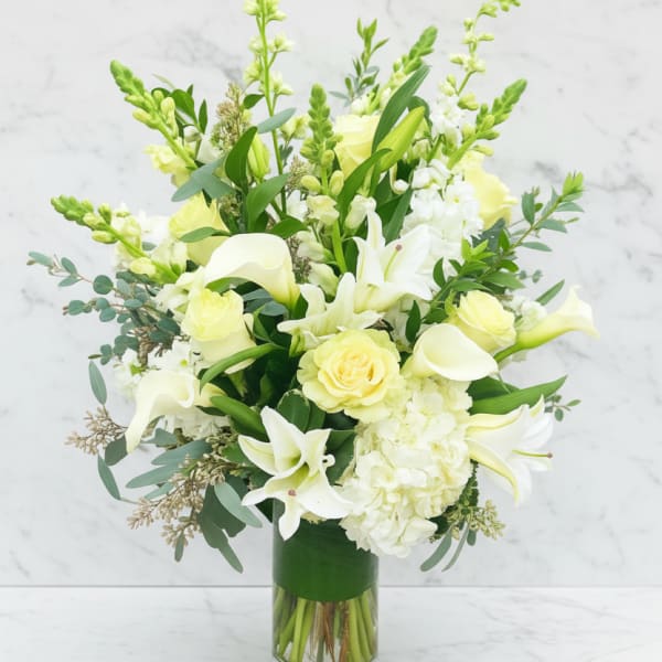 White and pale yellow flowers arranged in a clear glass vase