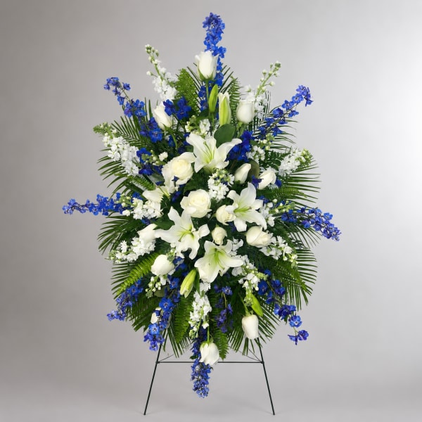 Standing floral spray with white lilies, roses, and blue flowers