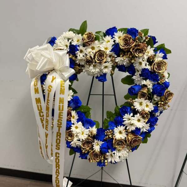 Heart-shaped floral wreath with blue, white, and gold flowers on a stand