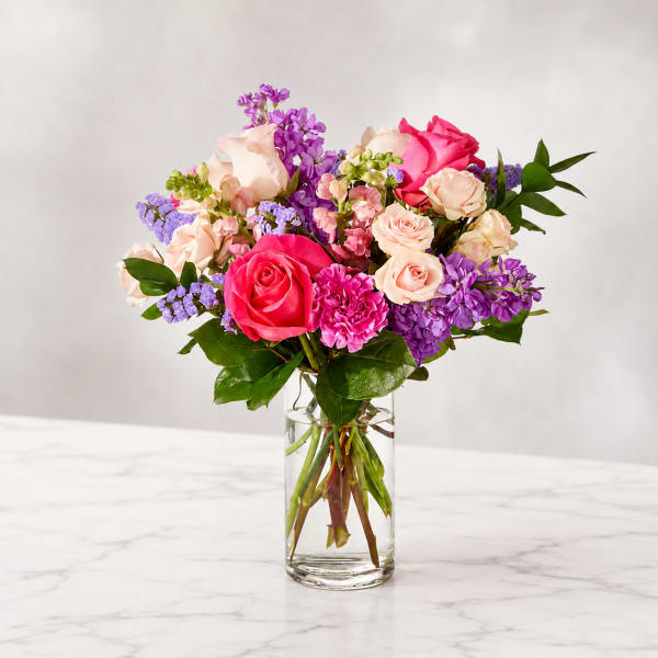 Bouquet of pink and purple roses in a clear glass vase