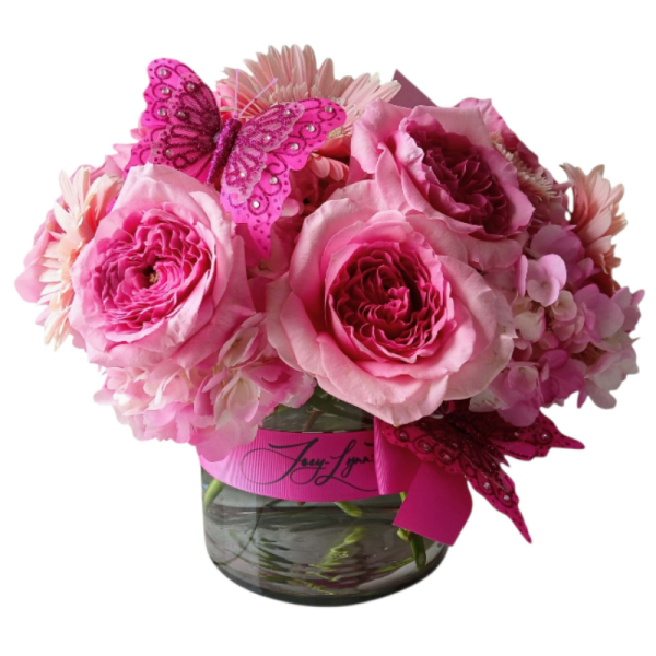 Pink roses and daisies in a glass vase with a pink butterfly decoration
