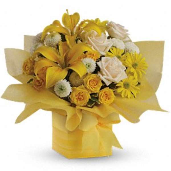 Yellow and white bouquet with lilies, roses, and daisies arranged in a yellow-wrapped square box.