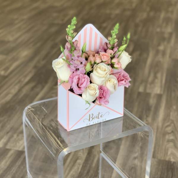 Pink and white roses in a striped gift box arrangement