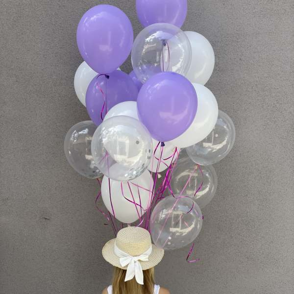 Cluster of lavender, white, and clear balloons held by a girl in a straw hat